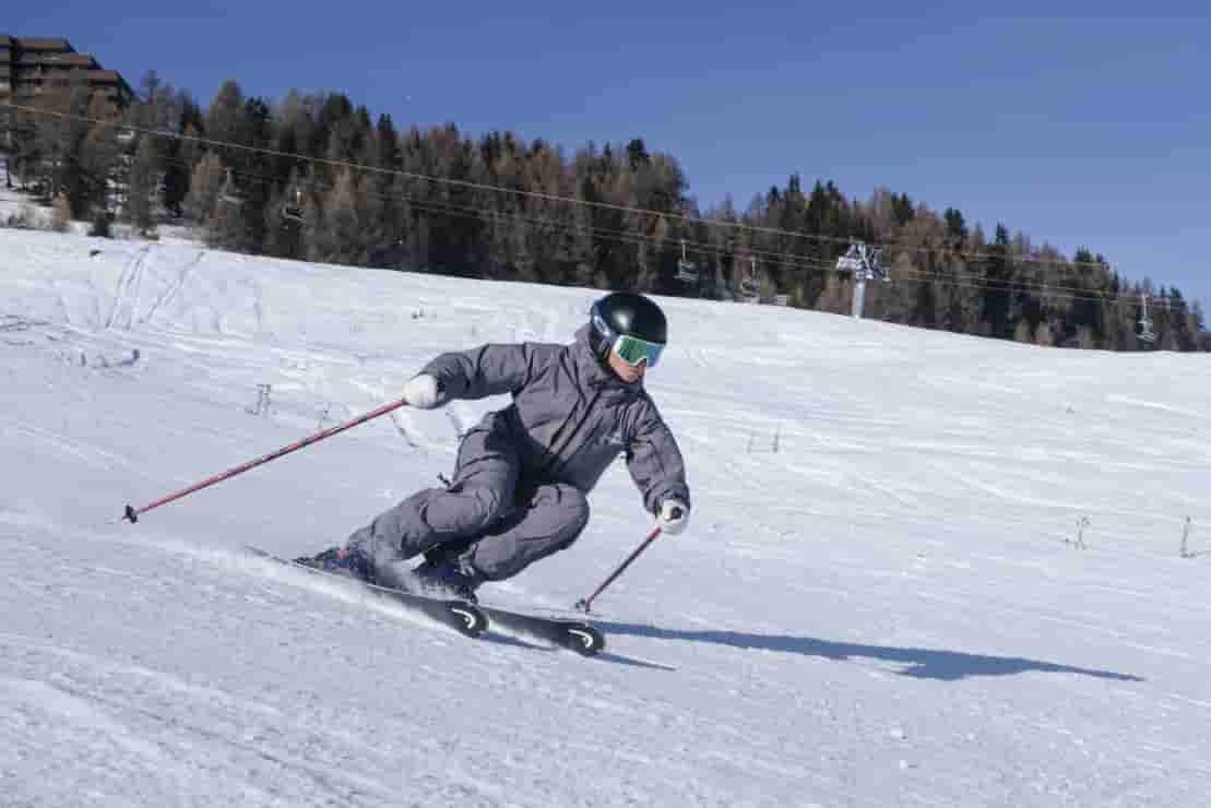 Private ski lesson in Nendaz with an instructor demonstrating carving technique on a groomed piste.